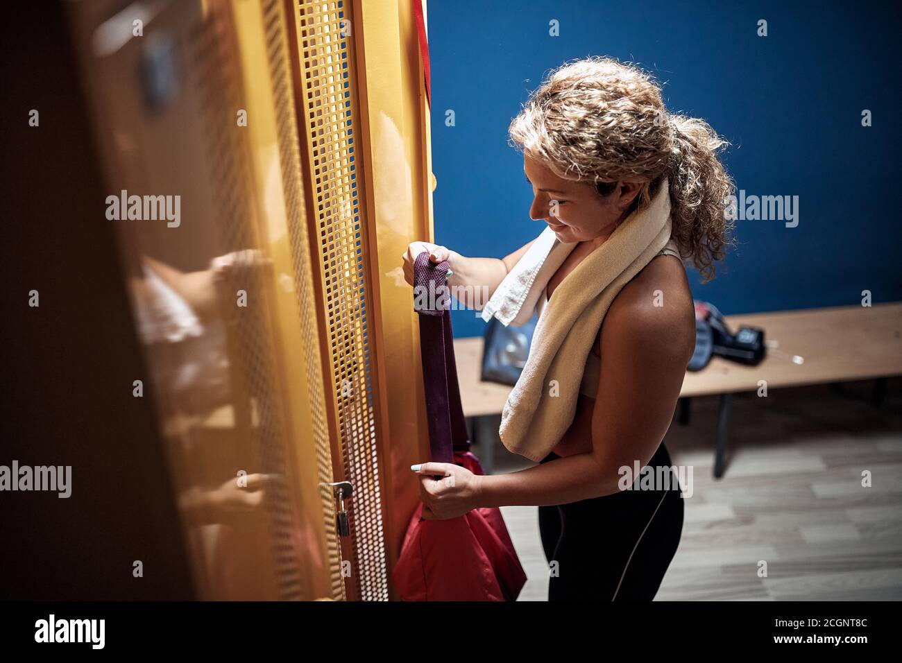 Jeune fille sportive dans un vestiaire prenant l'équipement pour une formation Banque D'Images