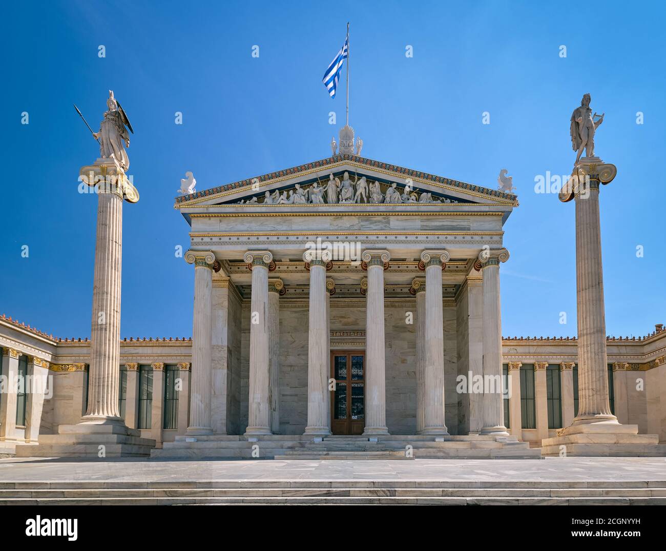 Entrée principale de l'Académie d'Athènes, centre national de recherche, colonnes avec Athéna, ancienne déesse grecque, et Apollon, ancien dieu grec. Drapeau grec Banque D'Images