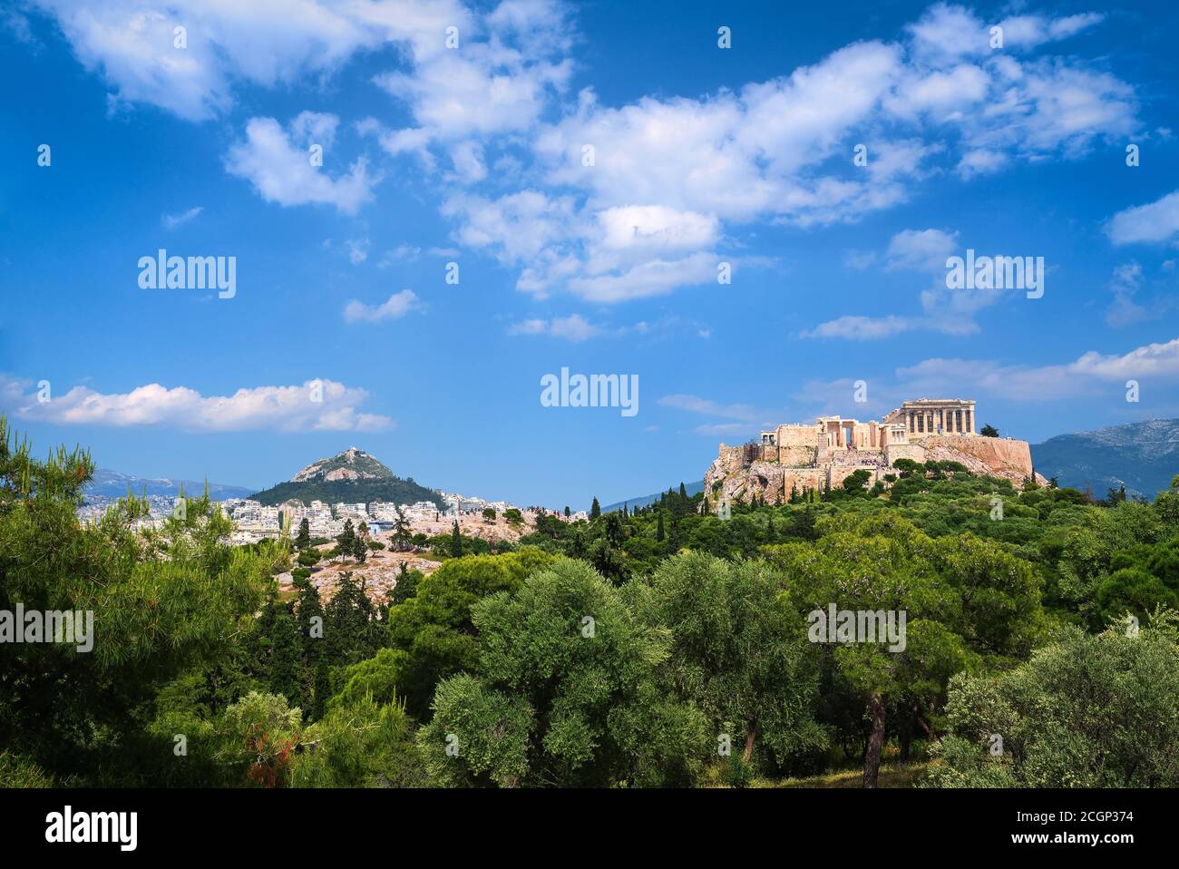 Vue emblématique de la colline de l'Acropole et de la colline du Lycabette en arrière-plan à Athènes, Grèce depuis la colline de Pnyx en été, avec de grands nuages dans le ciel bleu. Banque D'Images