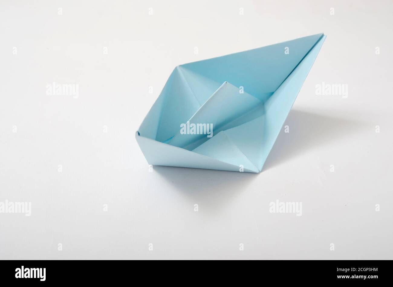 origami faire bateau, à partir de papier bleu clair, sur fond blanc. Images conceptuelles pour la vie de voile, les affaires, le stuggle, la survie et d'autres Banque D'Images