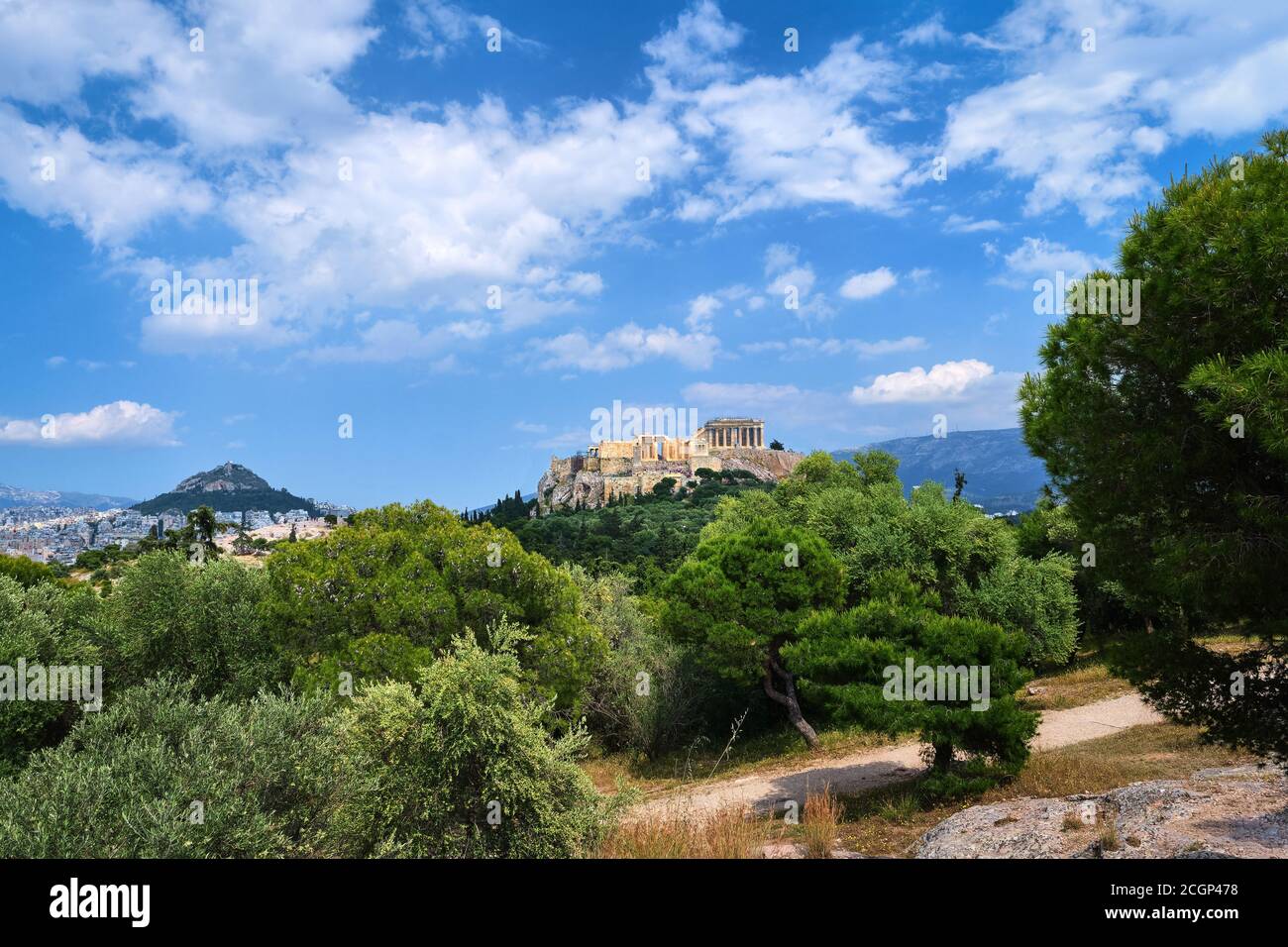 Vue emblématique de la colline de l'Acropole et de la colline du Lycabette en arrière-plan à Athènes, Grèce depuis la colline de Pnyx en été, avec de grands nuages dans le ciel bleu. Banque D'Images