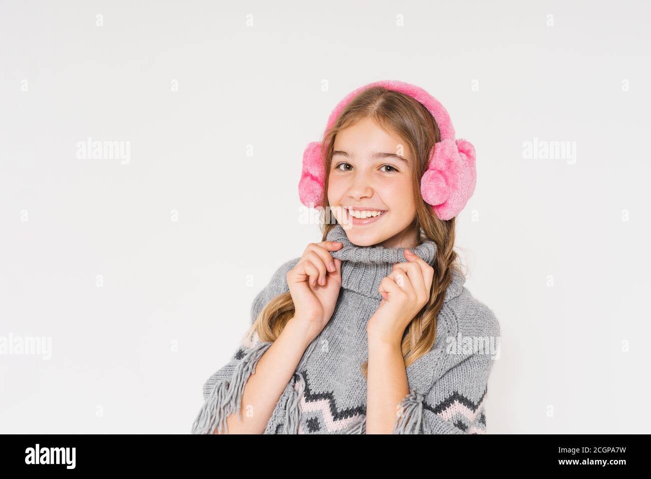 Adorable fille adolescente souriante dans un casque en fourrure rose et gris poncho est isolé sur fond blanc Banque D'Images