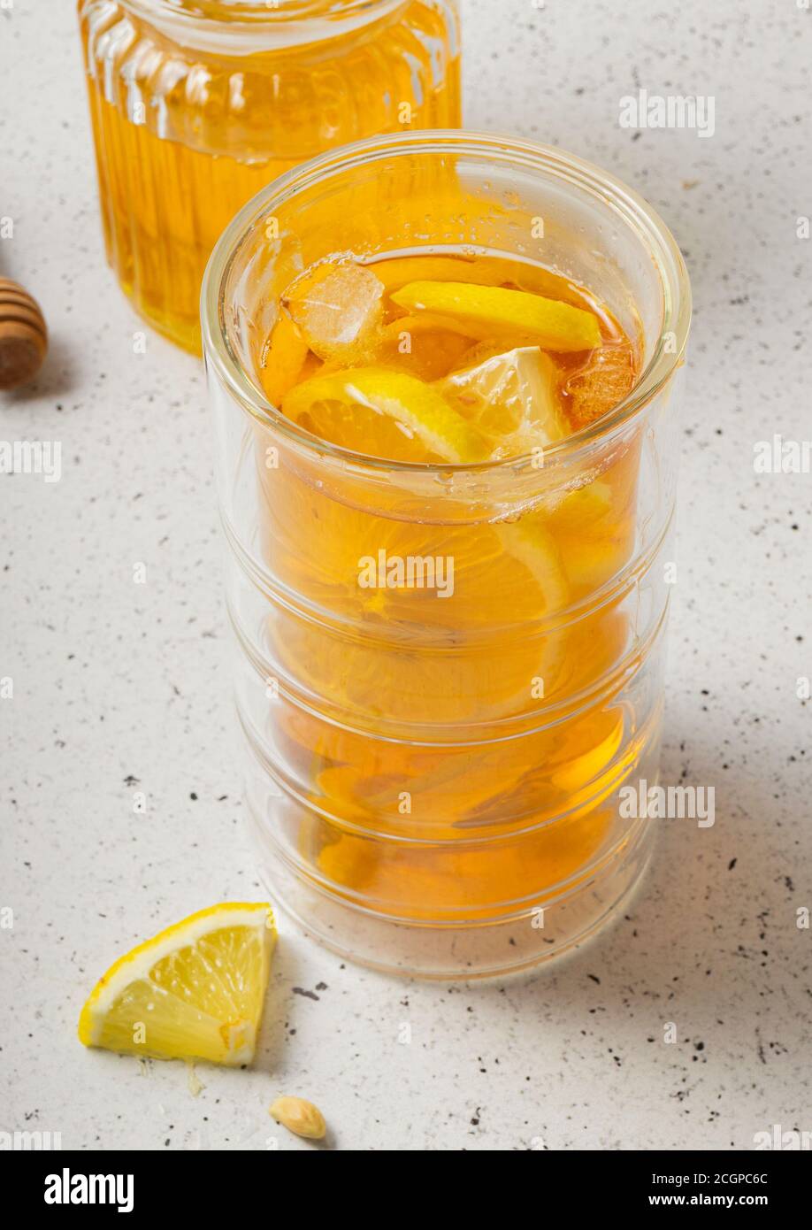 mise au point sélective, un grand verre de thé glacé au citron avec un pot de miel sur un fond clair Banque D'Images