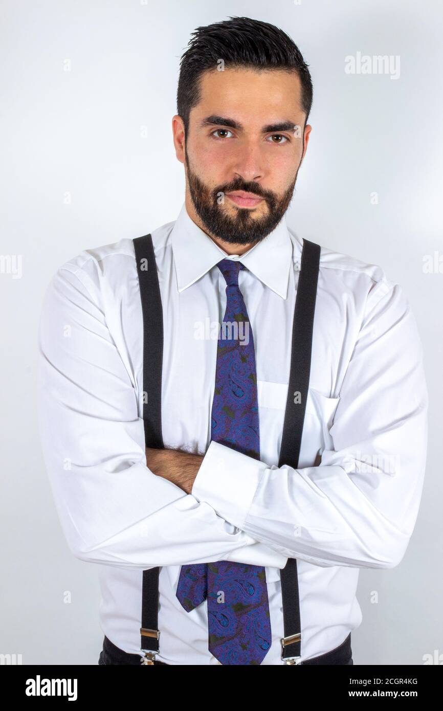 Beau jeune homme barbu en tenue formelle avec bras croisés. Homme  d'affaires élégant avec chemise, bretelles et cravate. Prise de vue  moyenne. Backgro blanc Photo Stock - Alamy