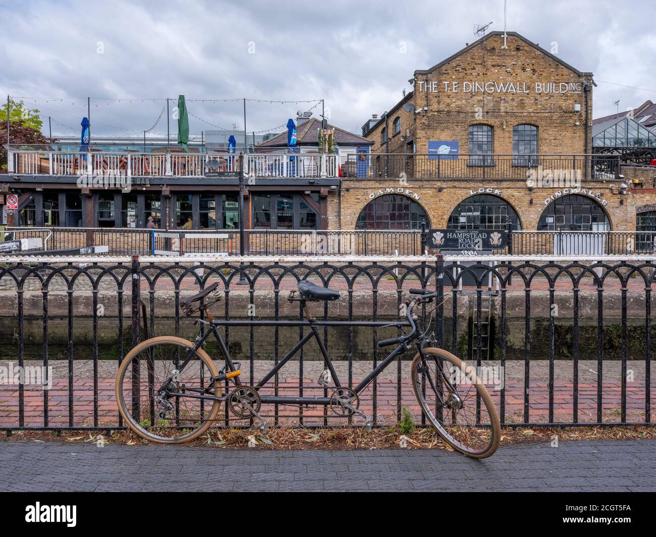 Un vélo tandem enchaîné aux rails à Hampstead Road Lock Sur le canal Regents avec Camden Lock Market dans le arrière-plan un lieu de vacances touristique populaire Banque D'Images
