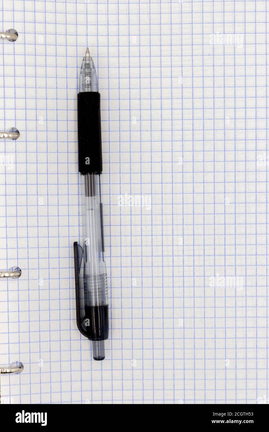 Feuille d'un bloc-notes dans une cage. Stylo à bille noir avec boîtier transparent. Feuille vierge dans un fond de cellule. Dominante bleue. Banque D'Images