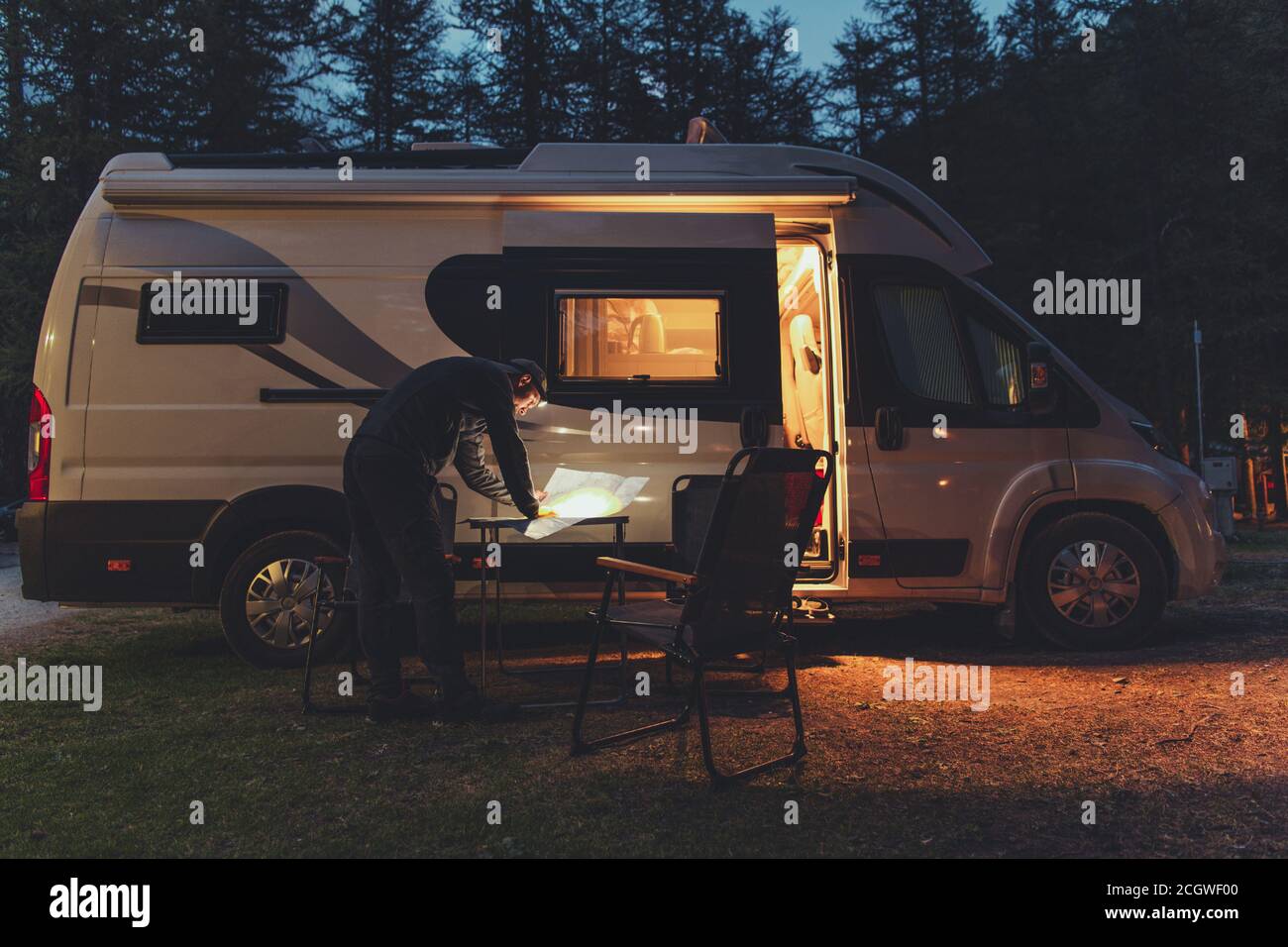 Caucasiens hommes dans ses 40 s de navigation de carte locale devant son véhicule de loisirs de camping-car Van pendant la soirée d'été plus froide. Thème du temps de camping. Banque D'Images