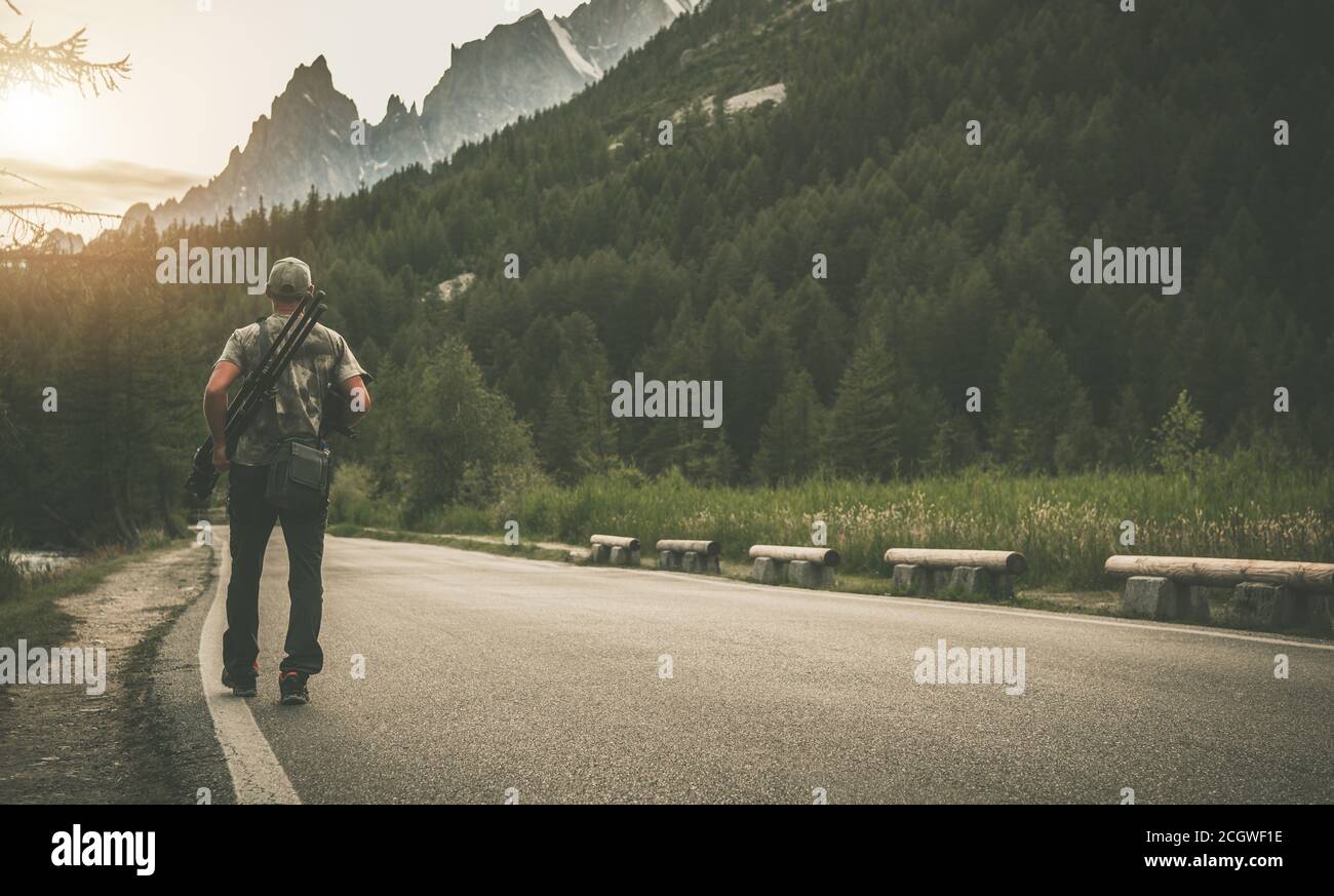 Un photographe de race blanche dans ses 40 ans avec des appareils photo numériques dans ses mains marchant le long de Mountain Road. Nature Photographie thème aventure. Banque D'Images