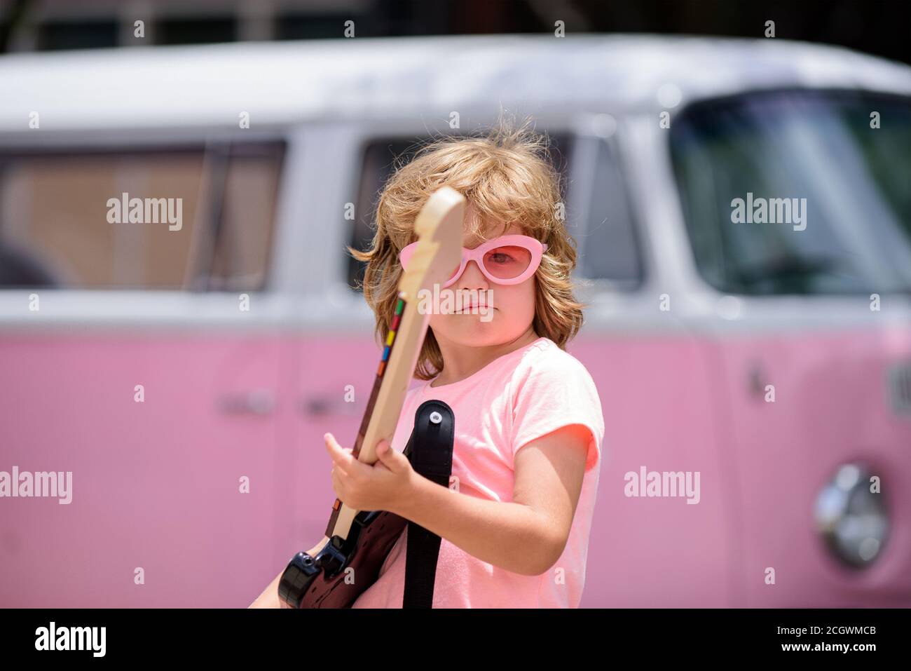 Joyeux enfant mignon improvisant. Petit garçon élégant enfant portant une chemise rose d'été, lunettes de soleil drôles s'amusant en ville. Hipster drôle. Banque D'Images