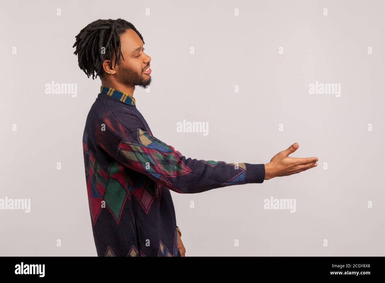Portrait de profil homme africain amical avec des dreadlocks s'étirant la main accueillant les invités avec le sourire torothy sur le visage, Ravi de vous rencontrer. Prise de vue en studio Banque D'Images