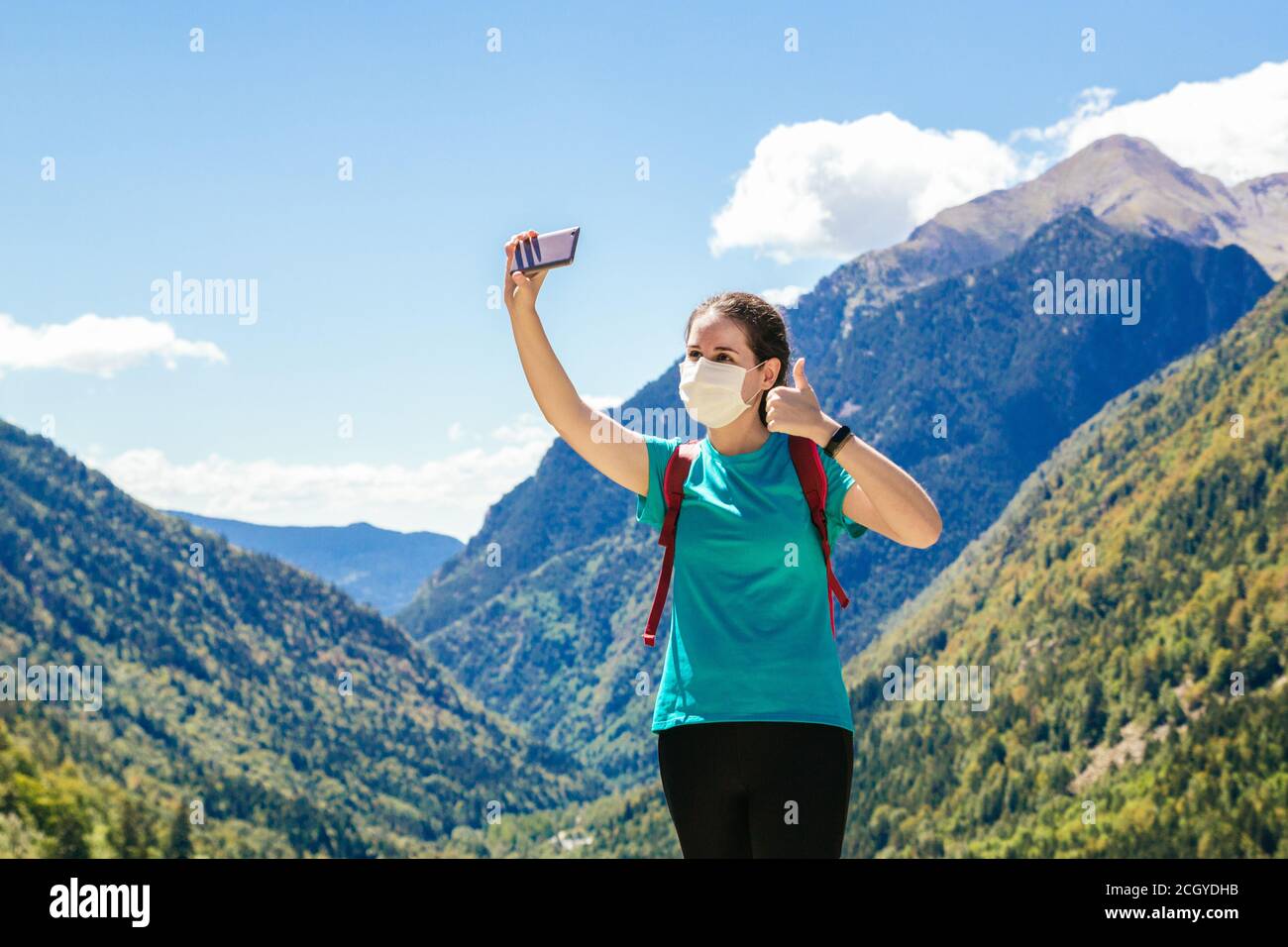 Photo d'une fille de randonneur prenant un selfie avec masque tout en appréciant une journée dans les montagnes et un beau paysage en arrière-plan Banque D'Images