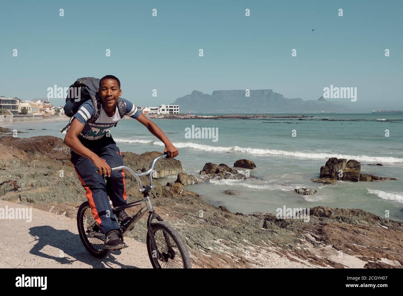 Les jeunes qui voyagent à vélo sur la très populaire plage de Bloubergstrand au Cap, en Afrique du Sud. Montagne de table en arrière-plan. Banque D'Images