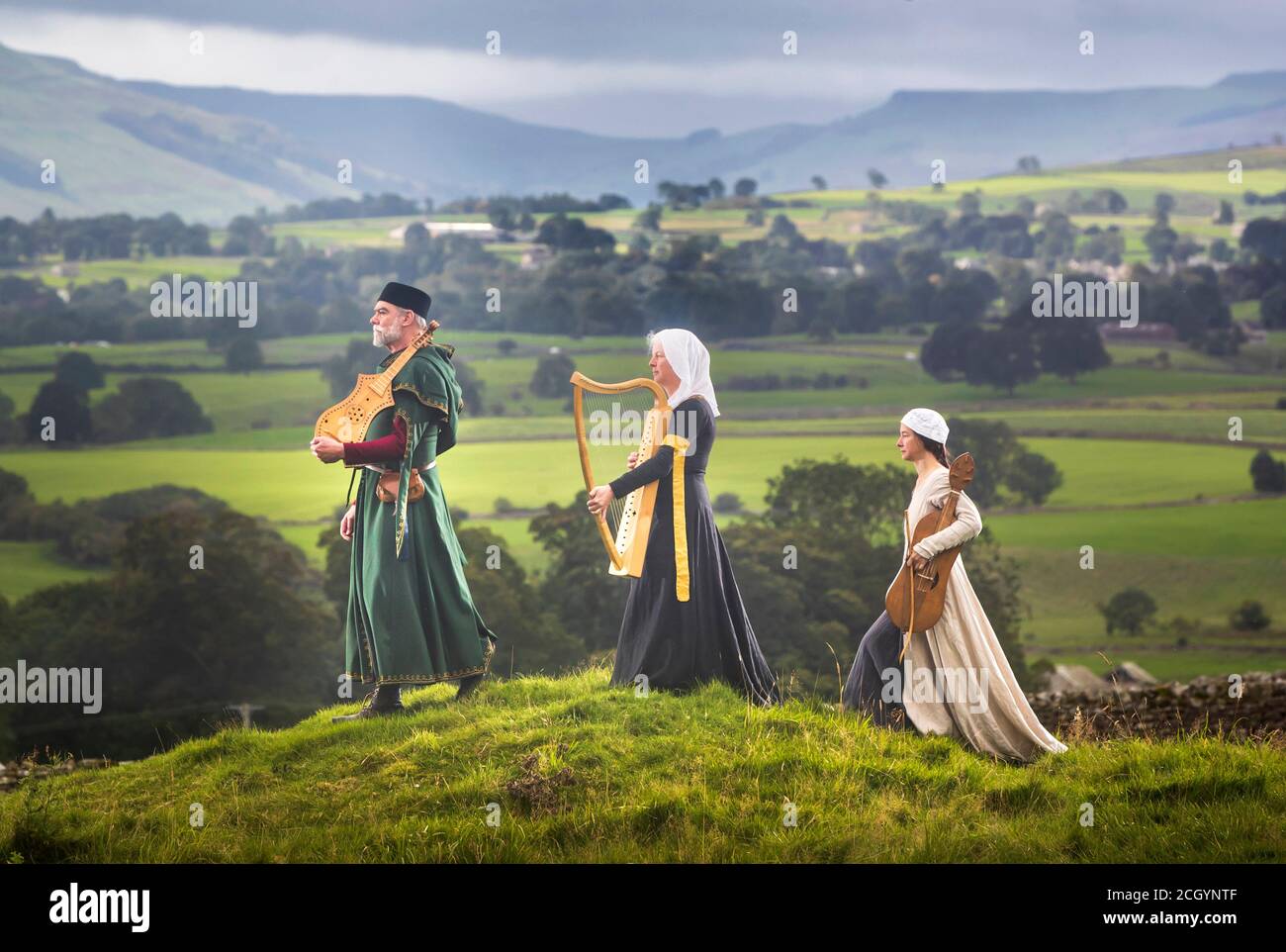 De gauche à droite Chris Elmes tient une citadelle, Cait Webb tient une harpe médiévale et Théodora Hidalgo avec une vielle médiévale, de l'ensemble médiéval gaita, porter des vêtements traditionnels dans le domaine du château de Bolton dans le North Yorkshire, avant de se faire jouer pendant la musique médiévale dans les Dales, Le festival de musique médiévale de l'Angleterre. Banque D'Images