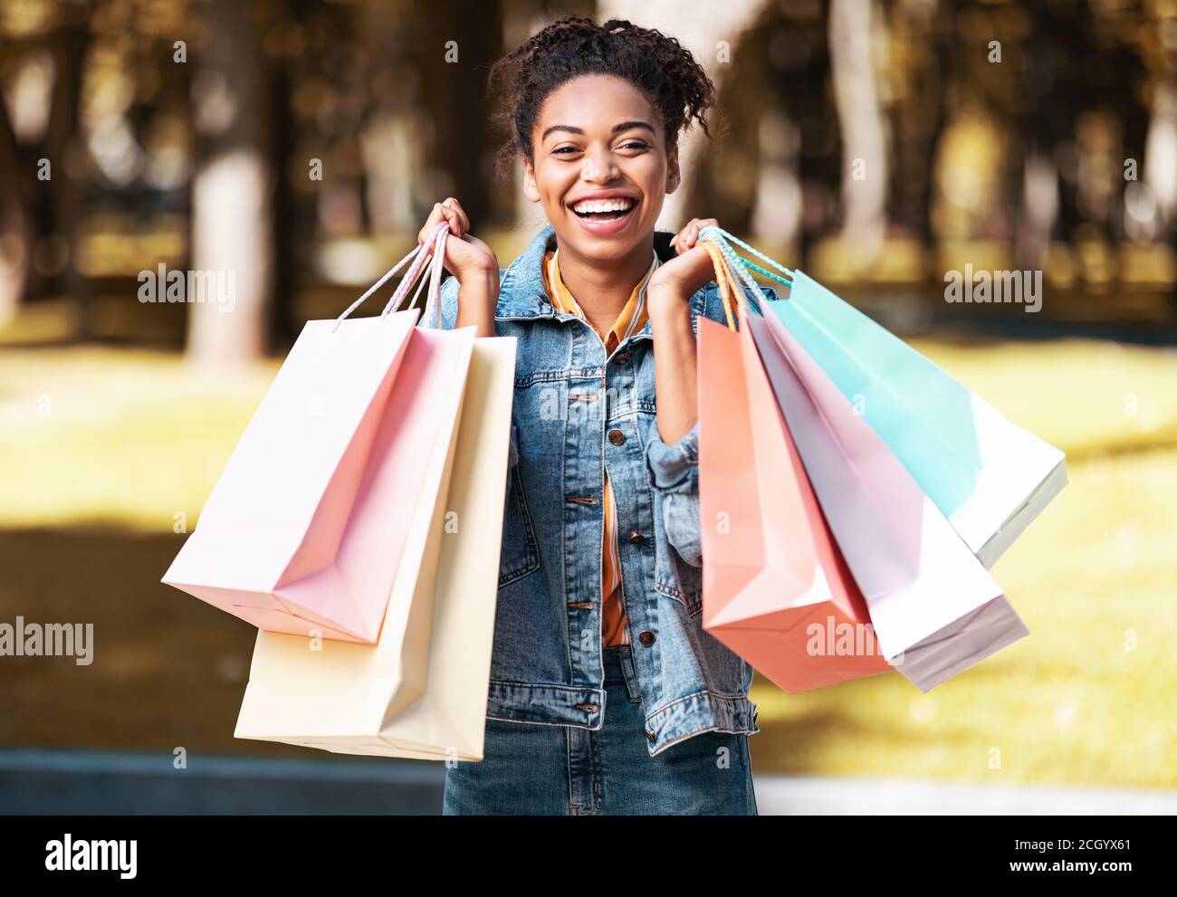 Joyeuse fille noire après avoir fait ses courses tenant des sacs de cabas  debout à l'extérieur Photo Stock - Alamy