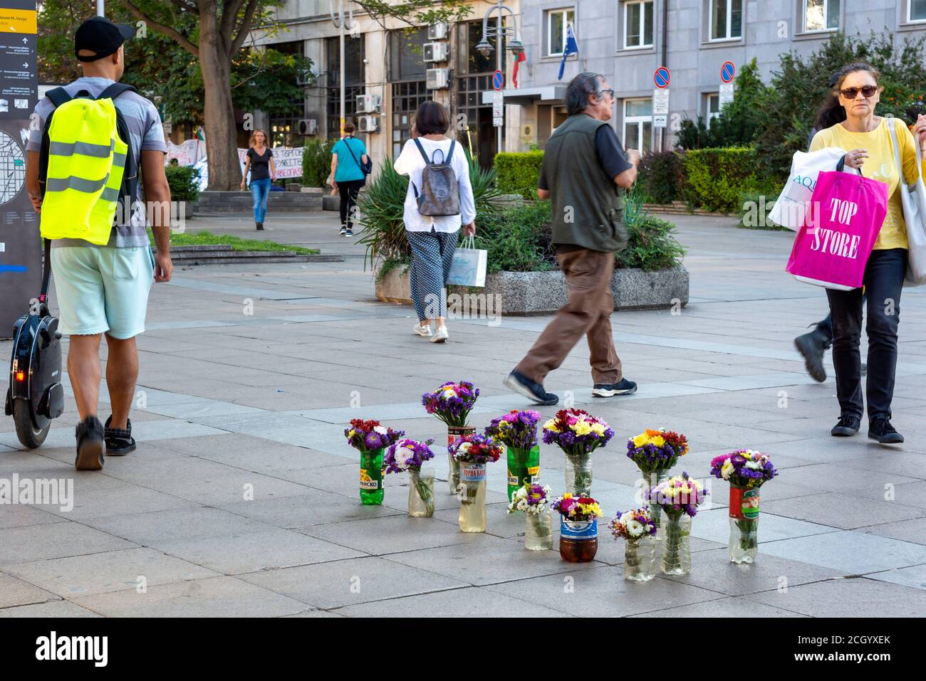 Piétons passant par des bouquets de fleurs pour la vente en exposition dans Vases en plastique impromptus sur la chaussée dans le centre de Sofia Bulgarie Banque D'Images