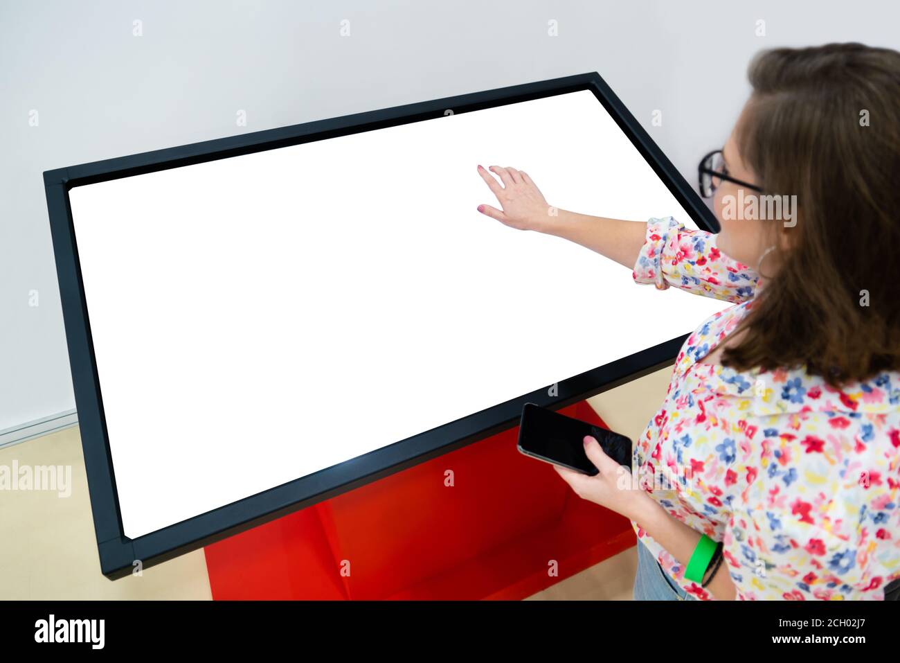Une femme avec un téléphone utilisant un kiosque sans contact en libre-service Banque D'Images