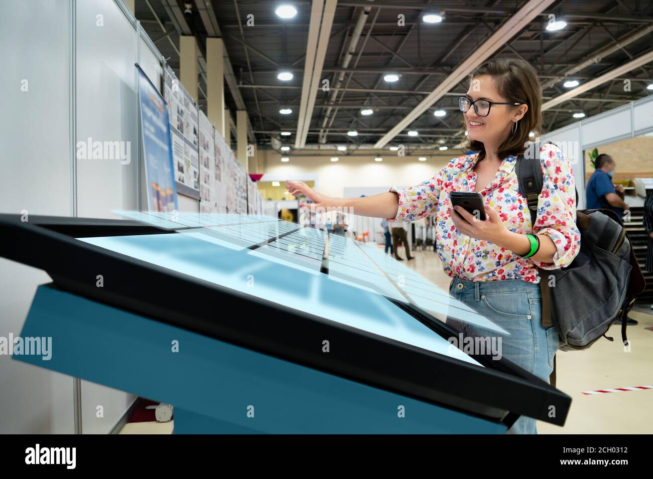 Une femme avec un téléphone utilisant un kiosque sans contact en libre-service Banque D'Images
