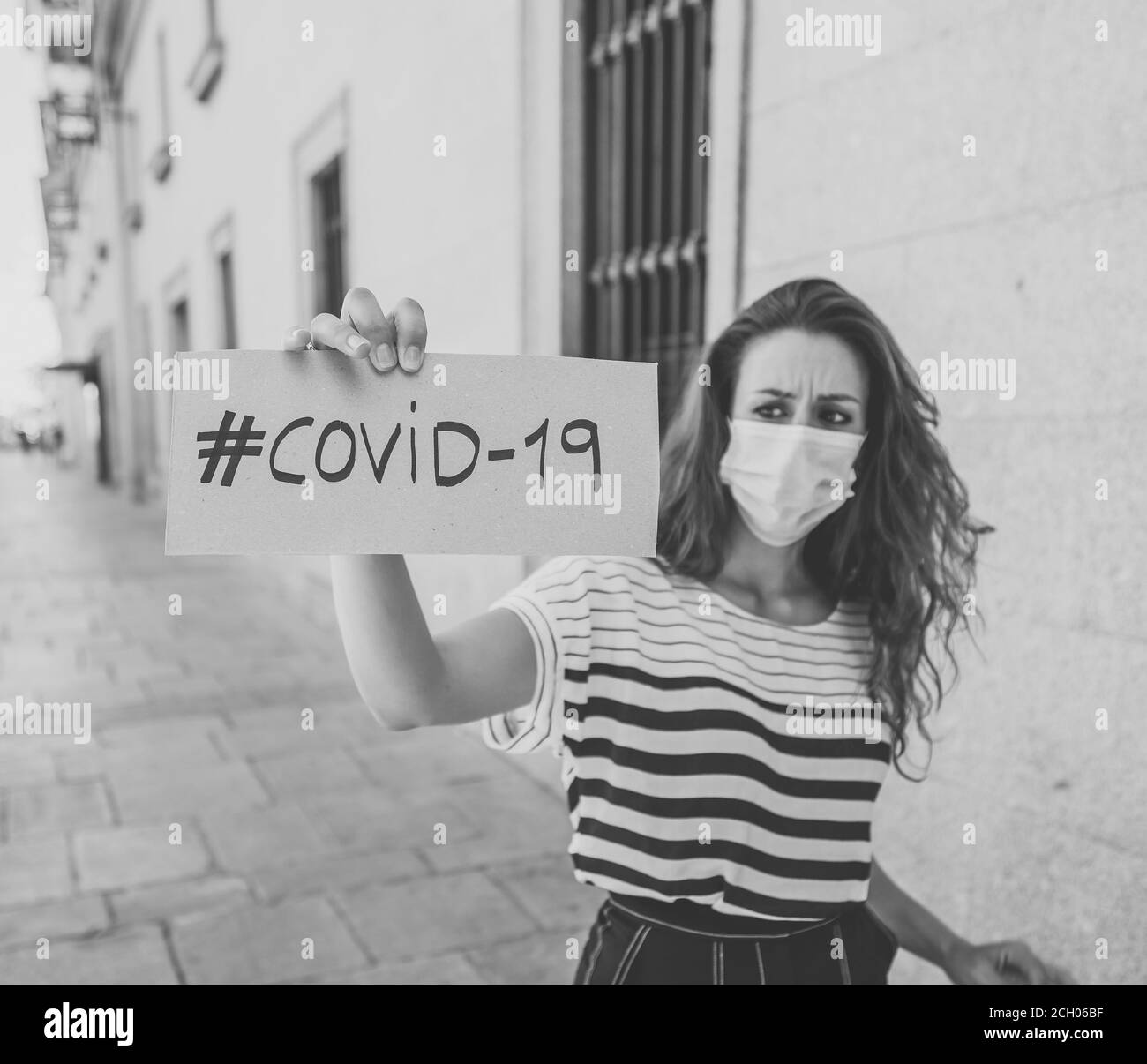 Portrait de la triste femme dépressive dans un masque médical de protection du visage portant le signe COVID-19. Épidémie de coronavirus, chômage, santé et économie mondiale Banque D'Images