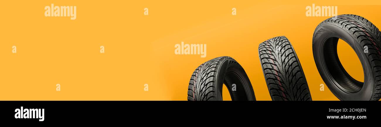 trois pneus à friction, redémarrage en hiver, sur fond orange vif. copier le panorama de l'espace pour l'en-tête du site Banque D'Images