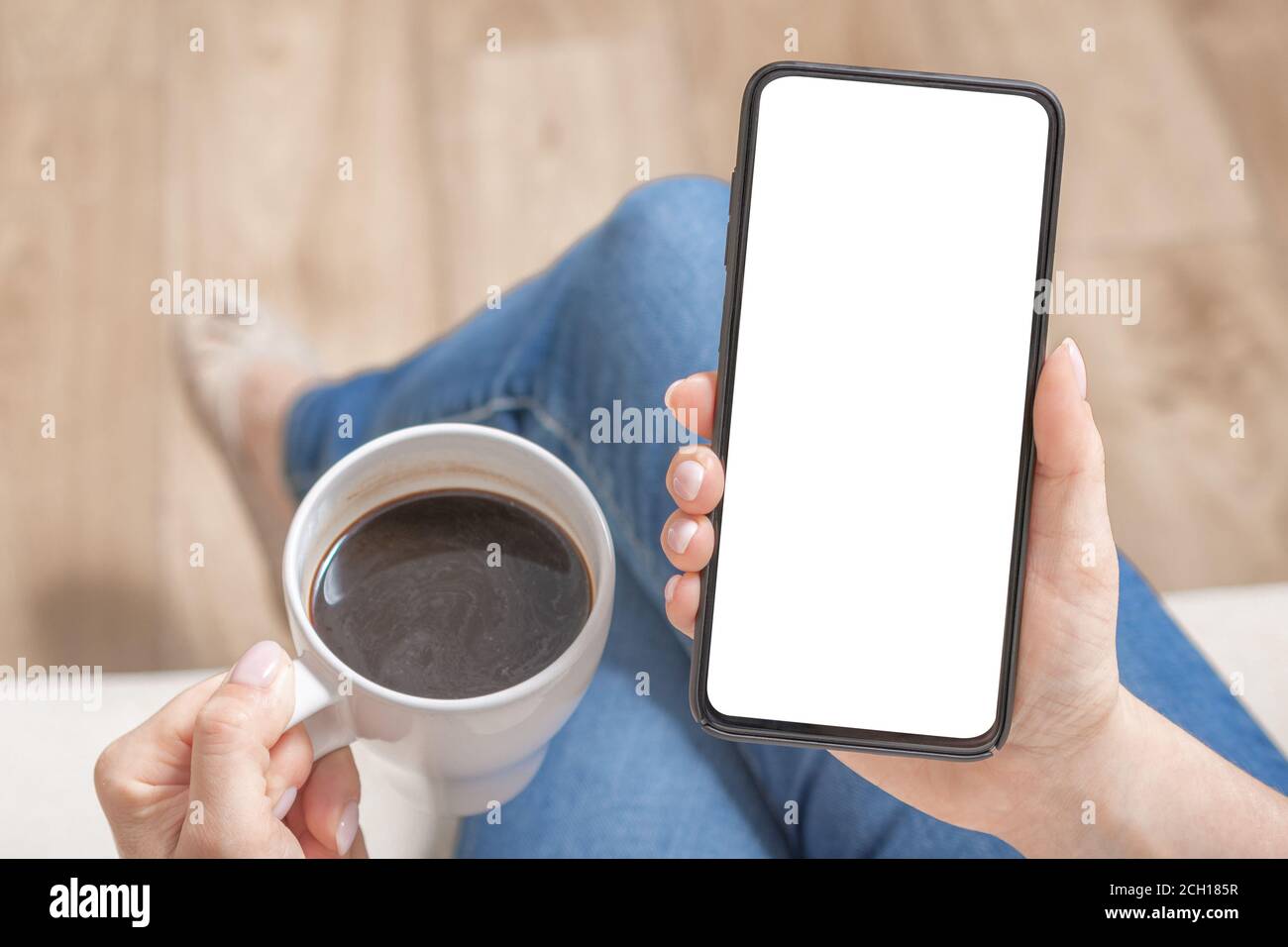 Image de maquette d'une femme tenant un téléphone portable noir avec écran blanc vierge dans un café. Vue rognée des mains d'une femme tenant un smartphone avec une co vierge Banque D'Images