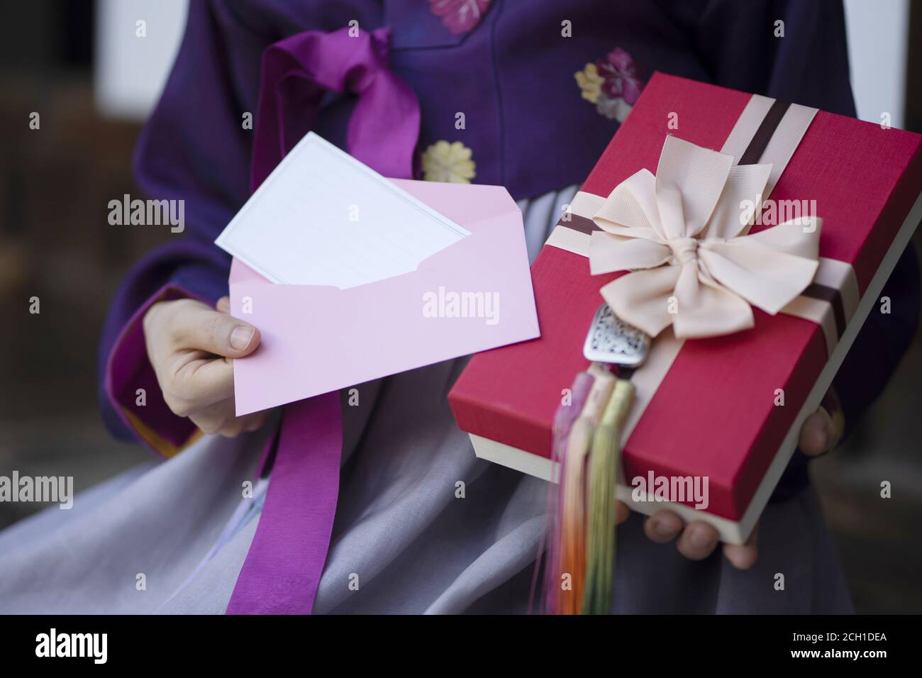 Une femme vêtue de vêtements traditionnels coréens tient un bon cadeau avec un cadeau boîte Banque D'Images