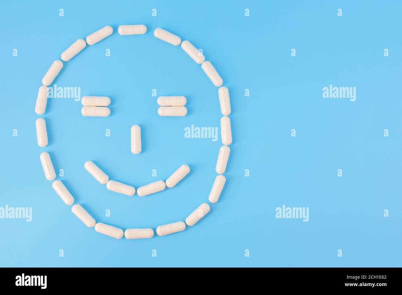 Capsules disposées en smilng visage. Visage souriant fait de pilules blanches sur fond bleu. Le concept de bonne santé, de rétablissement de la maladie, de guérison, Banque D'Images