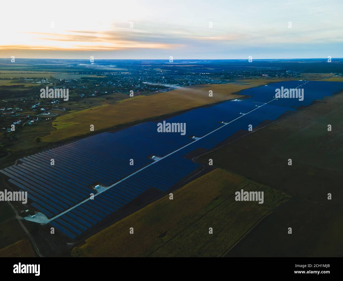 Vue aérienne de drone dans de grands panneaux solaires dans une ferme solaire dans un grand champ sur la campagne au coucher du soleil clair. Centrales solaires, photo colorée Banque D'Images