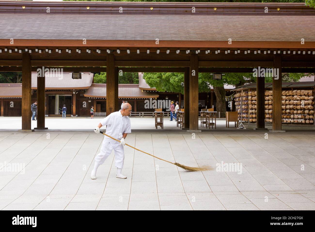 Harajuku, Tokyo / Japon - 16 juin 2018 : un vieil homme balaie le terrain du temple Meiji-jingu avec un balai de paille ou d'herbe. Banque D'Images