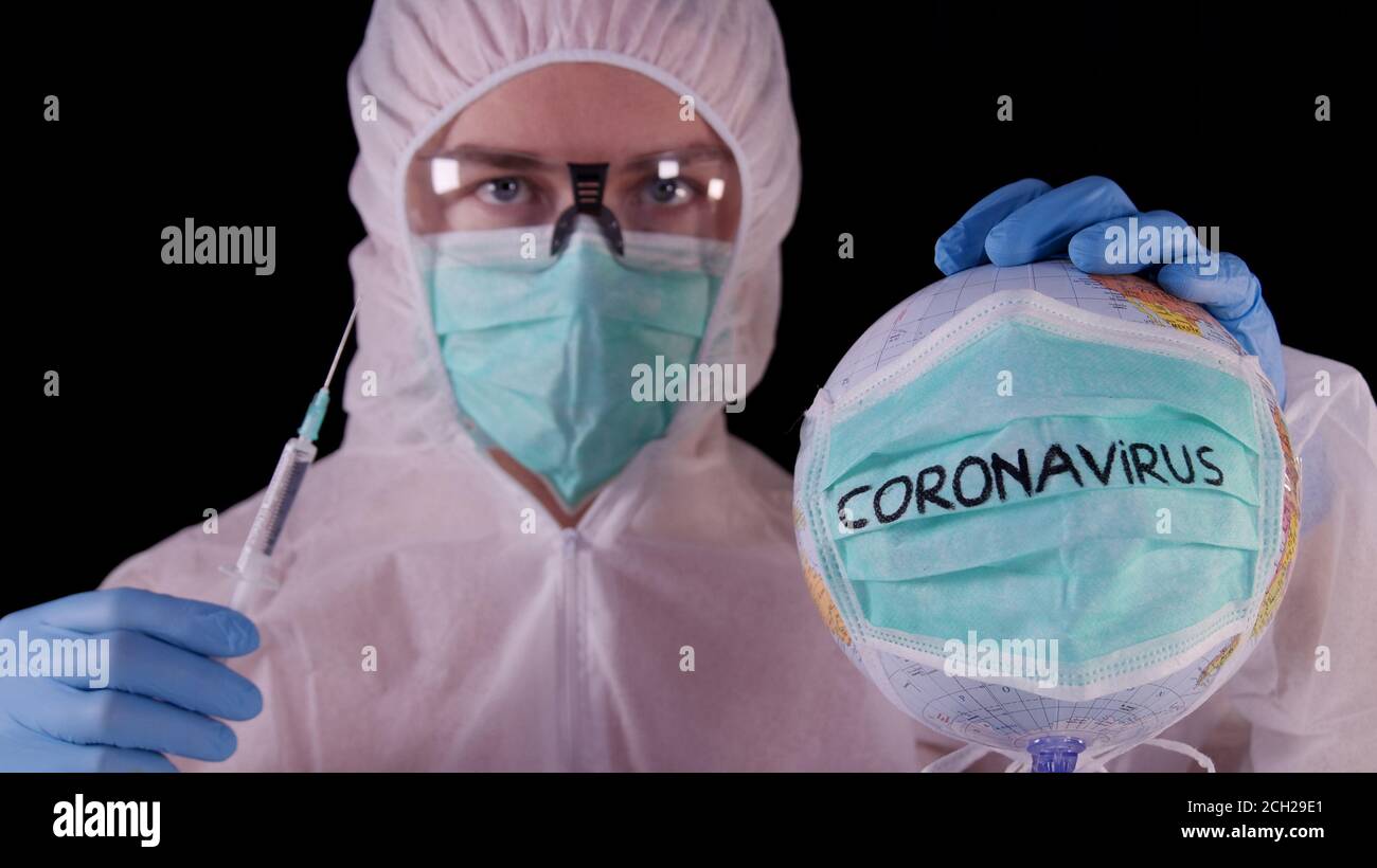 Vaccin contre le coronavirus. Homme en uniforme de sécurité blanc, masque et lunettes contenant une ampoule et une seringue de vaccin contre le coronavirus. Concept de guérison pandémique COVID-19 Banque D'Images