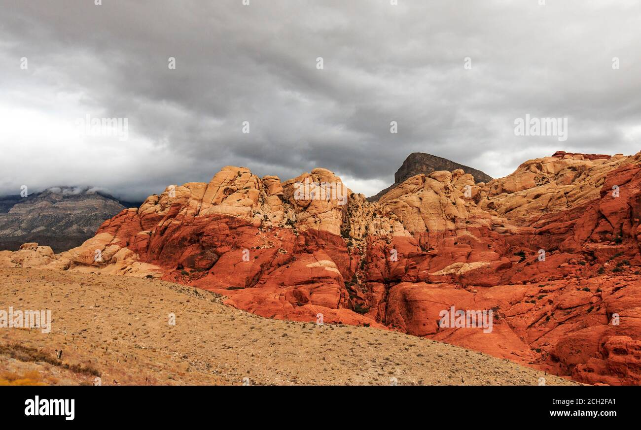 Des nuages orageux se ferment sur les collines Calico de la zone nationale de conservation de Red Rock Canyon, à 20 kilomètres à l'ouest de Las Vegas, NV, États-Unis. Le rouge dans les roches est causé par la percolation de l'eau souterraine à travers le fer oxydé dans les roches. Banque D'Images