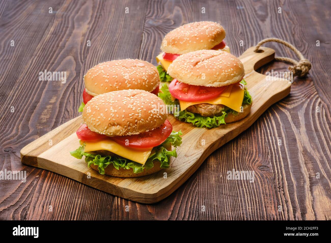 Quatre hamburgers faits maison sur une table de service en bois Banque D'Images