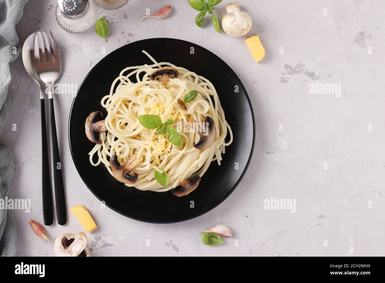 Spaghetti aux champignons et basilic sur plaque noire sur fond gris, vue de dessus Banque D'Images