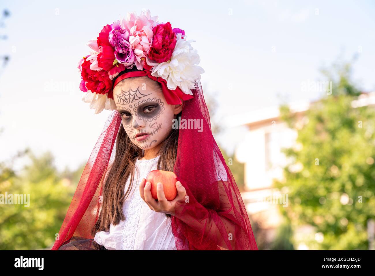 Jeune fille de sullen avec la peinture d'halloween sur le visage et beau fleurs sur la tête Banque D'Images
