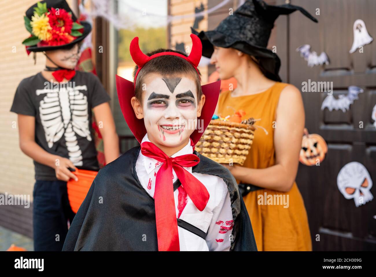 Garçon joyeux en costume d'halloween vous regardant contre les jeunes femme et ami Banque D'Images