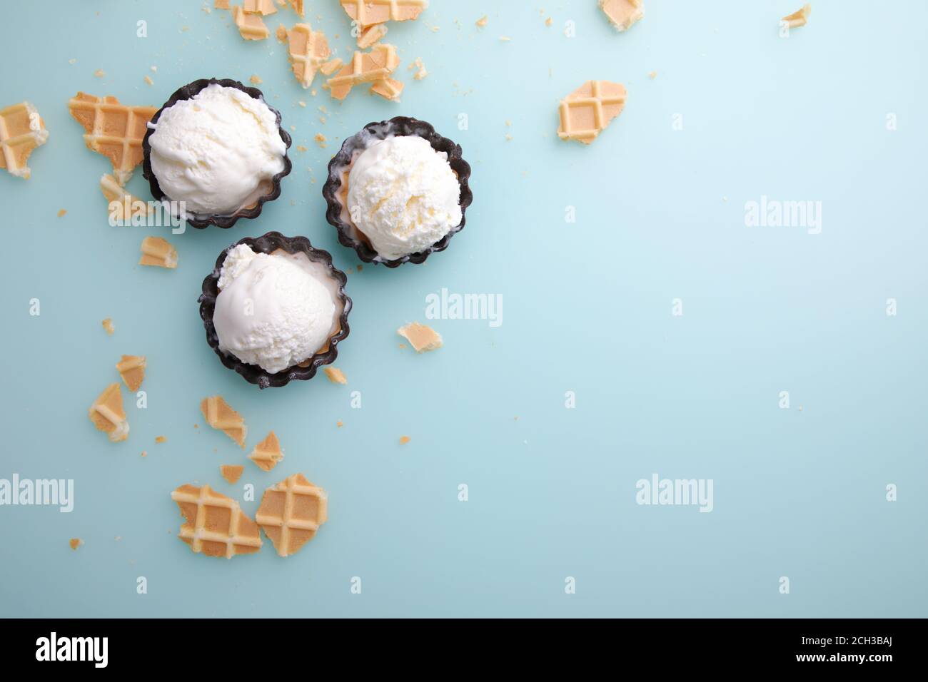 Vue de dessus des boules de glace à la vanille en gaufre et bol à chocolat sur fond bleu Banque D'Images