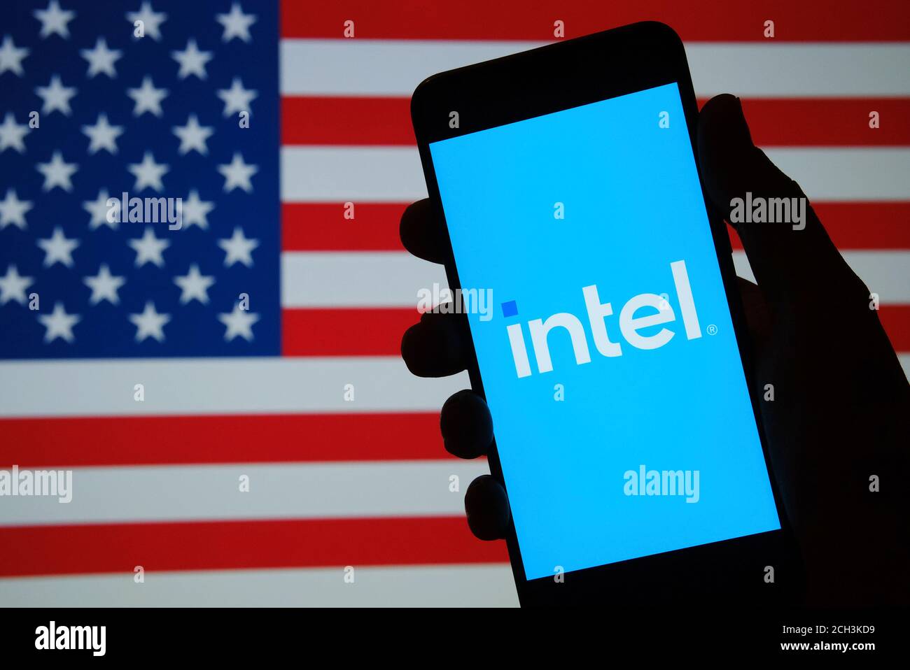 Stafford / Royaume-Uni - 2 septembre 2020 : nouveau logo Intel vu sur la silhouette du téléphone tenir à la main et drapeau américain flou sur fond flou. reb. Intel Banque D'Images