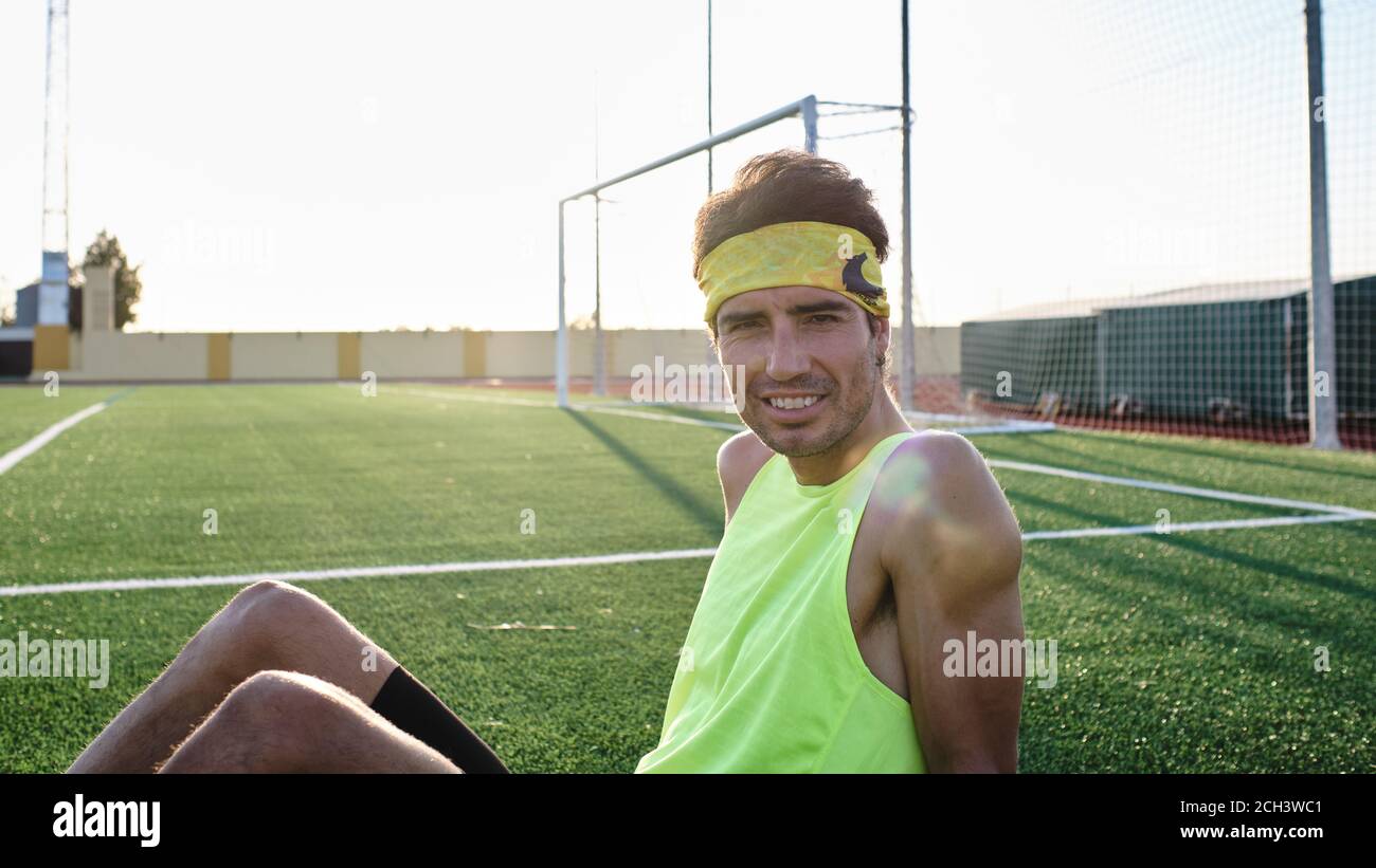 un jeune garçon de vêtements de sport assis sur l'herbe regarde appareil photo Banque D'Images