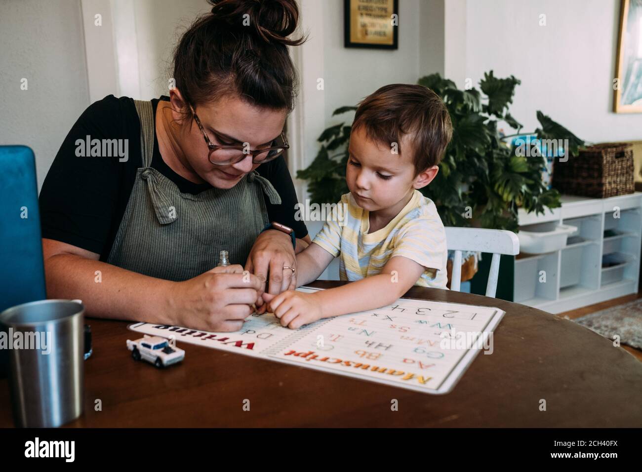 Maman et jeune fils peignant des ongles à la table de cuisine Banque D'Images