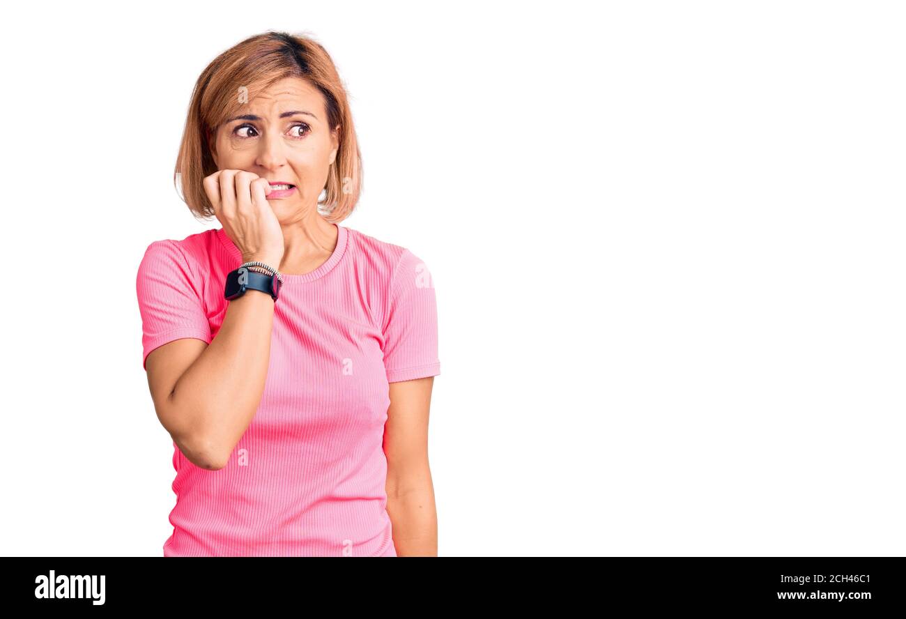 Jeune femme blonde portant des vêtements de sport semble stressée et nerveuse avec les mains sur la bouche piquant les ongles. Problème d'anxiété. Banque D'Images