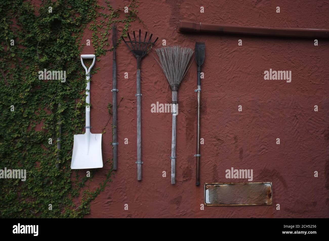 Les outils de jardinage accrochés au mur de ciment rouge. Banque D'Images