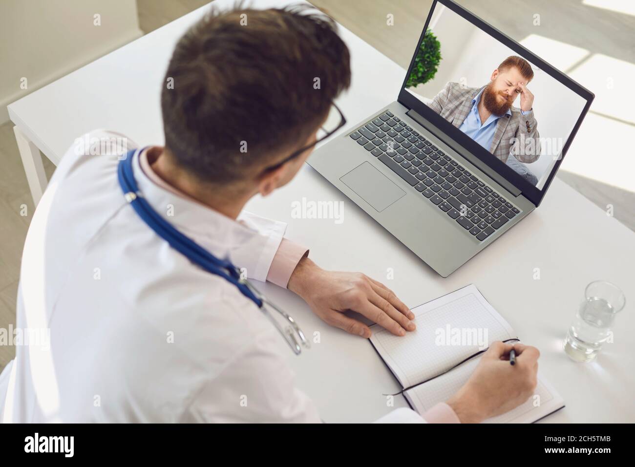 Médecin de l'hôpital donnant la consultation en ligne au patient utilisant ordinateur portable moderne Banque D'Images