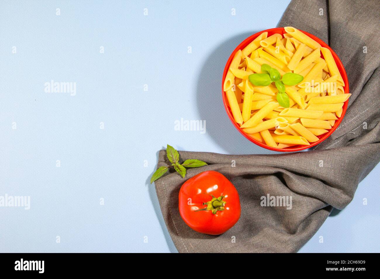 Pâtes et ingrédients pour cuisiner sur fond bleu, vue du dessus. Cuisine italienne. Pâtes, tomates, basilic, légumes. Copier l'espace Banque D'Images