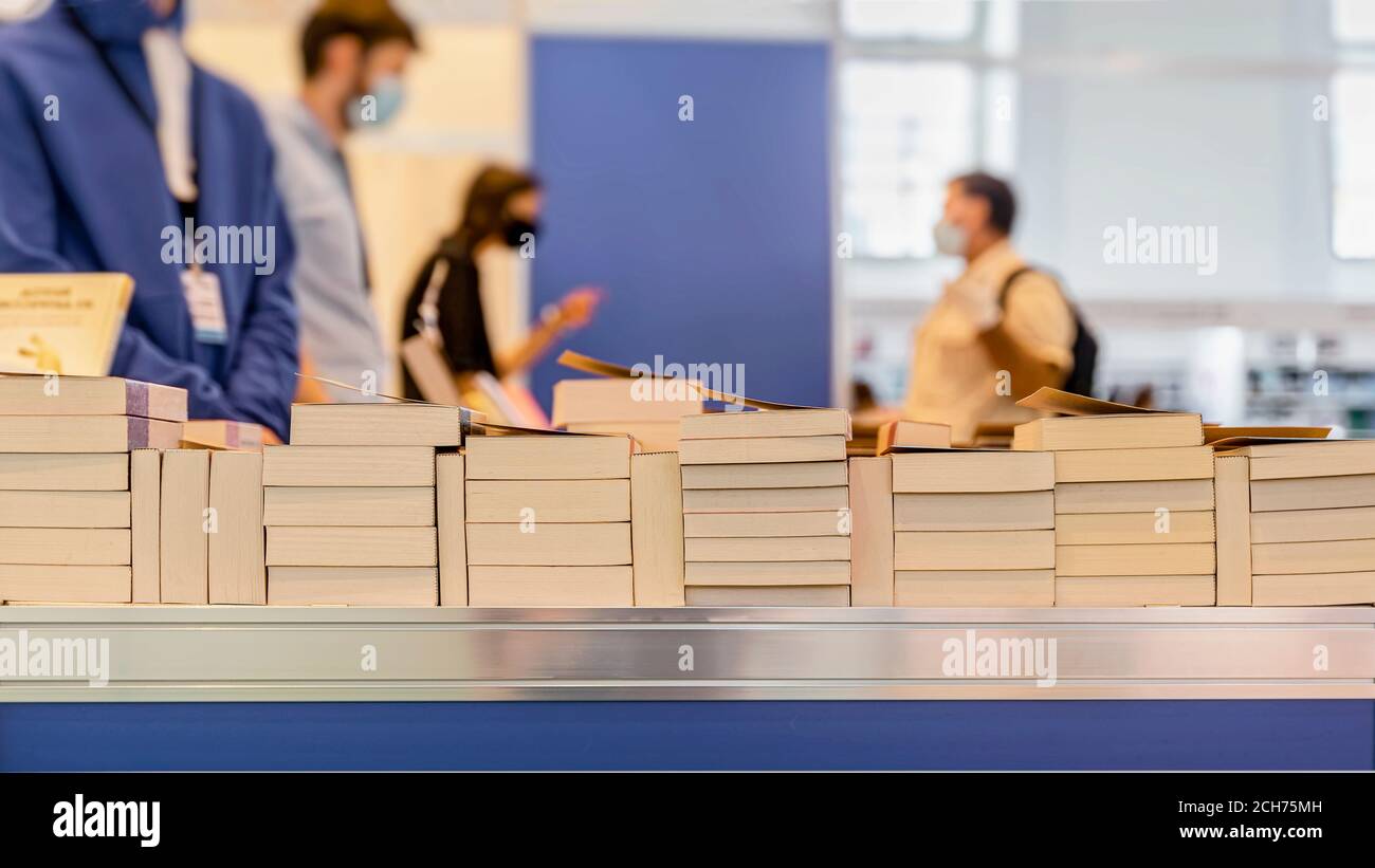 Librairie abstraite floue. Piles de livres, acheteurs de masques médicaux de protection et de gants. Concept de nouvelle norme, protection contre les maladies virales Banque D'Images