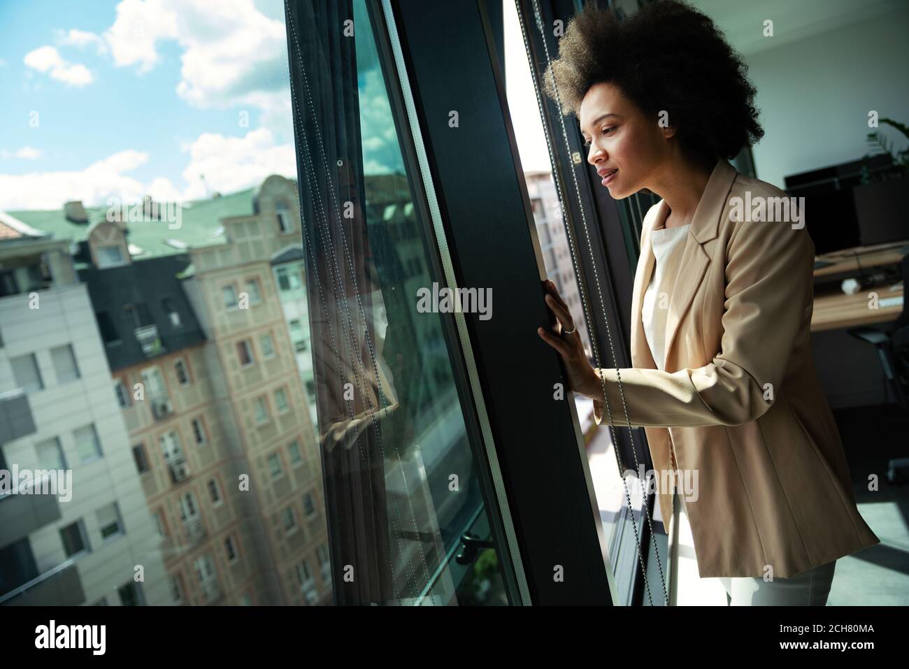 Belle femme d'affaires africaine regardant à l'extérieur de la fenêtre dans le bureau Banque D'Images