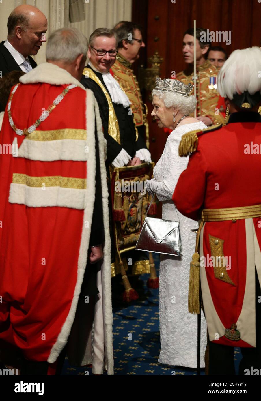 La reine Elizabeth II parle au leader de la Chambre des communes Chris Grayling (à gauche) et au secrétaire à la Justice Michael Gove (à gauche), alors qu'elle marche à travers le porche normand avant l'ouverture du Parlement, à la Chambre des Lords, au Palais de Westminster à Londres. Banque D'Images