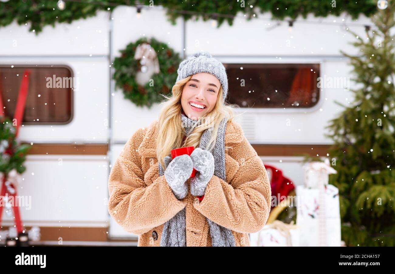 Conte de fées d'hiver. Femme souriante buvant du thé à l'extérieur et regardant les chutes de neige Banque D'Images