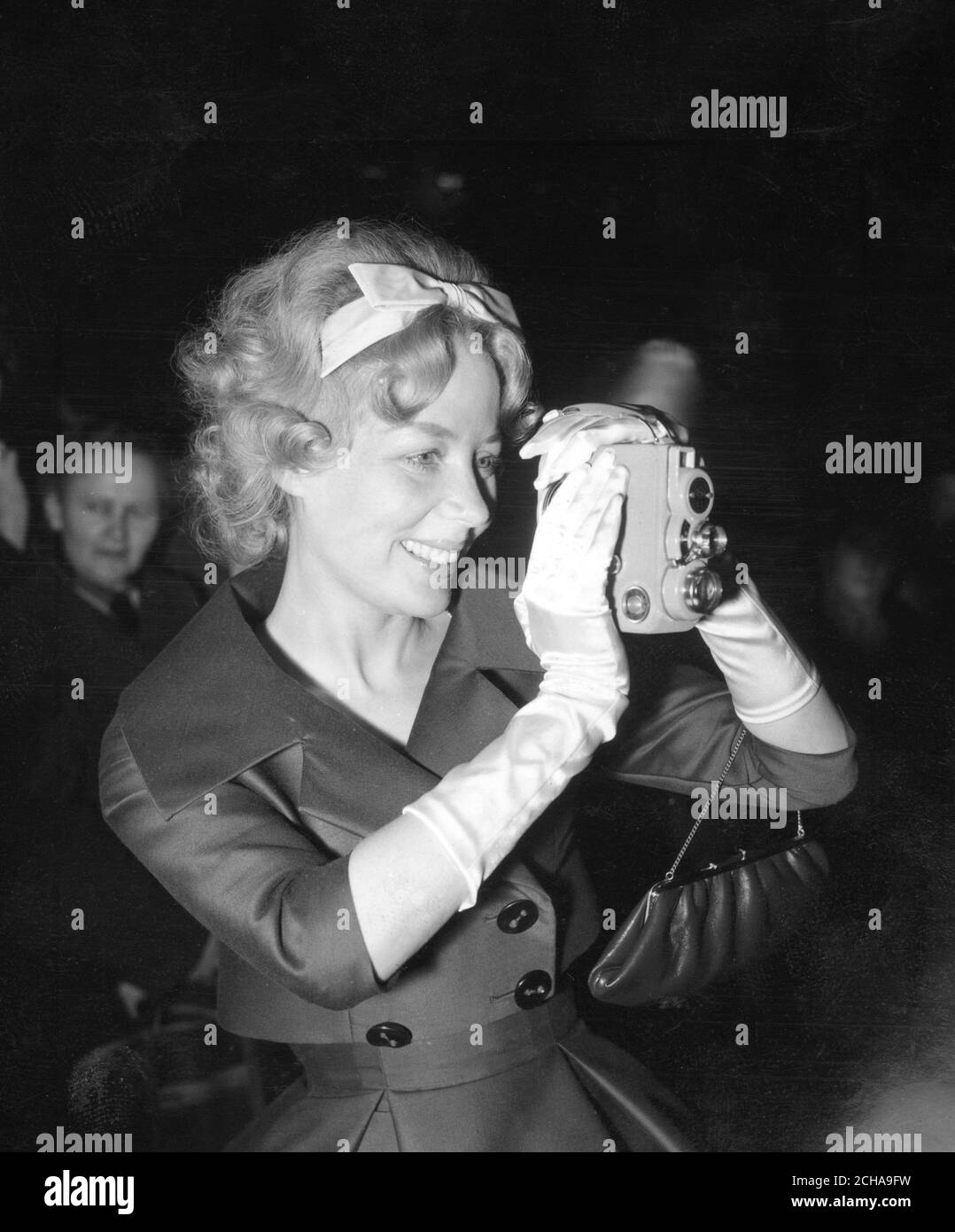 Babs Beverley, de la Beverley Sisters, utilise une caméra ciné pour filmer l'arrivée de sa sœur jumelle Teddie au bureau de caisse de Caxton Hall, à Londres, pour son mariage avec Peter Felix, un chirurgien dentaire londonien de 35 ans et champion britannique du ski nautique. Banque D'Images