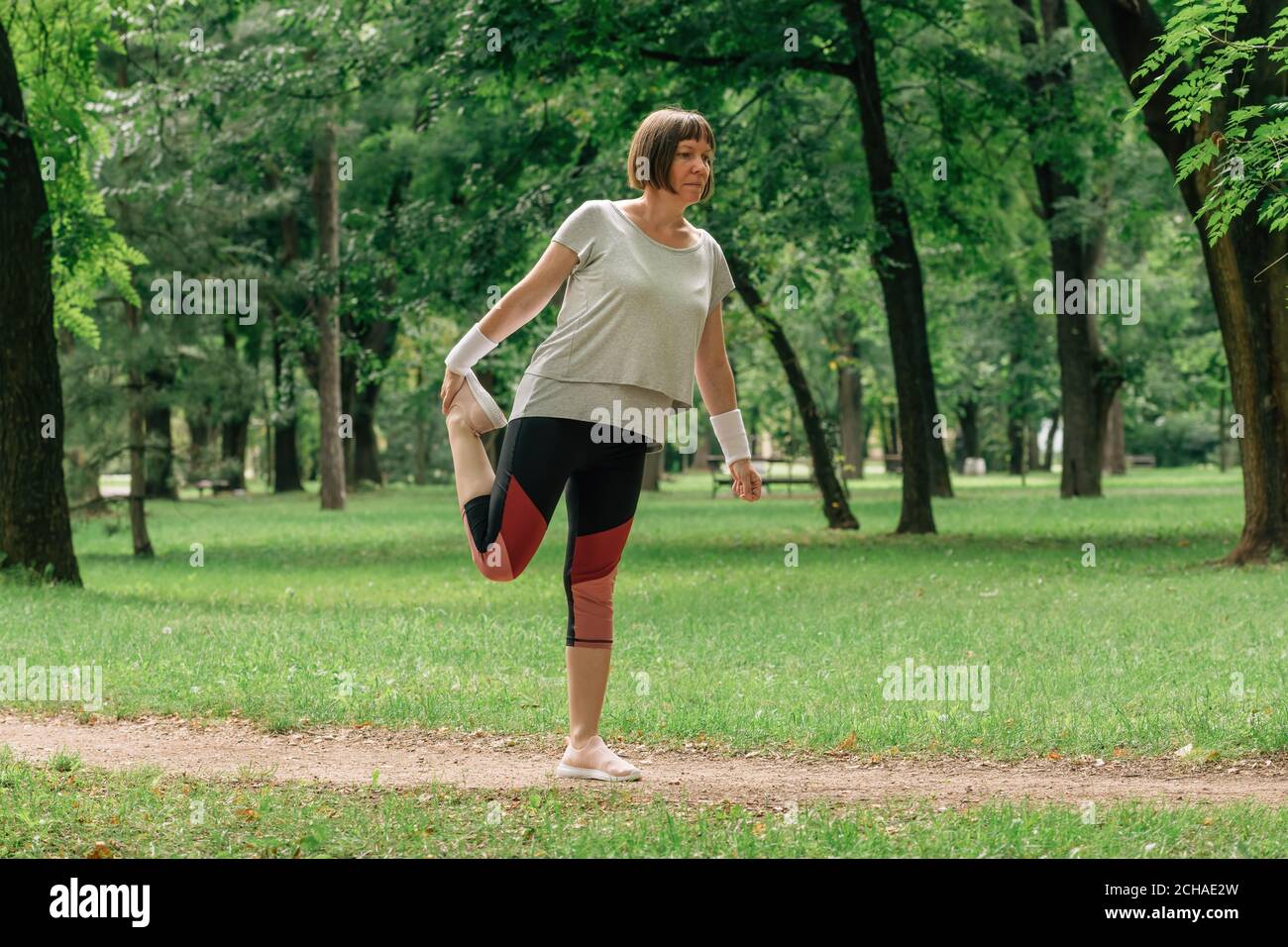 Jogging féminin qui étire les muscles et se réchauffe pour faire de l'exercice de course dans le parc, mise au point sélective Banque D'Images