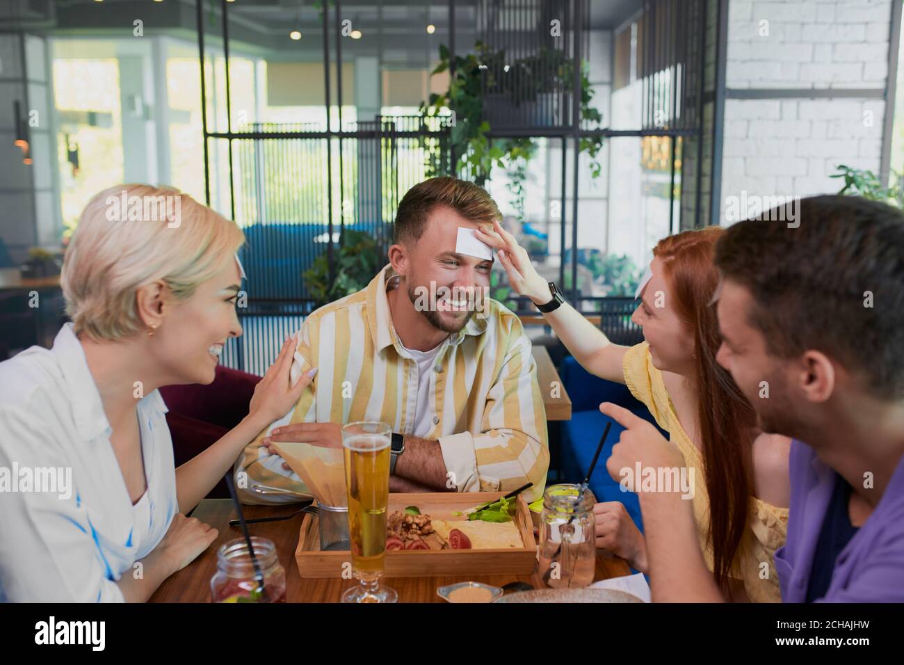 Les amis jouent ensemble qui je suis dans le café, temps de loisirs. Humour, concept de divertissement Banque D'Images