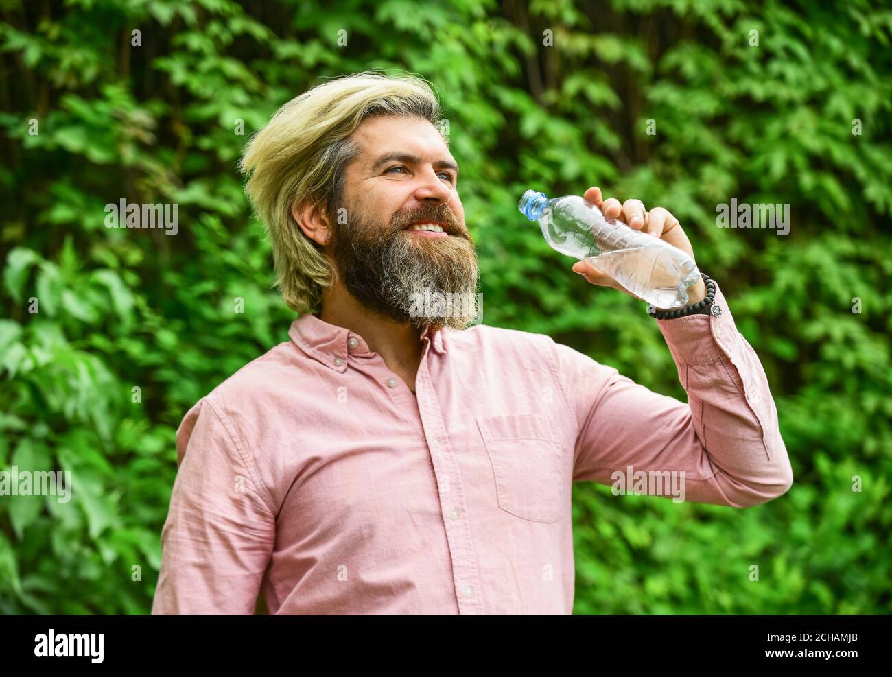 il suffit de sourire. un barbu tient une bouteille d'eau en plastique. il a soif. buvez un peu d'eau pendant que vous marchez dans le parc. rafraîchissez-vous. Maintenir l'équilibre de l'eau dans le corps. Brutaux hipster mâle boire de l'eau. Banque D'Images